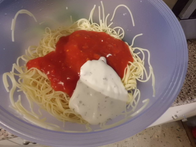 Spaghetti mit Zigeunersauce und angerichteten Joghurtdressing vermischen